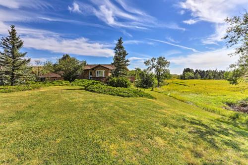 a large grassy field with a house in the background at Rapid City Vacation Home with Wraparound Deck! in Rapid City