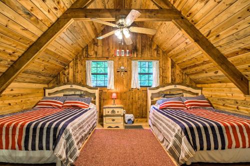 two beds in a room with a ceiling fan at Tellico Plains Cabin - 25 Acres, Backyard Creek! in Tellico Plains