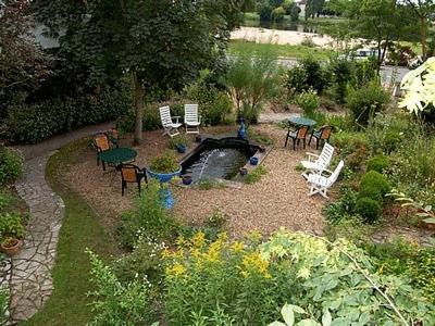 a garden with chairs and tables and a pond at Le Grand Monarque in La Charité-sur-Loire