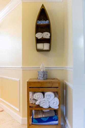 a bathroom with a shelf with towels and a mirror at Home by Beach 5 - The Treehouse in Naples