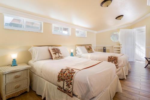 two beds in a bedroom with white walls and windows at Home by Beach 5 - The Treehouse in Naples