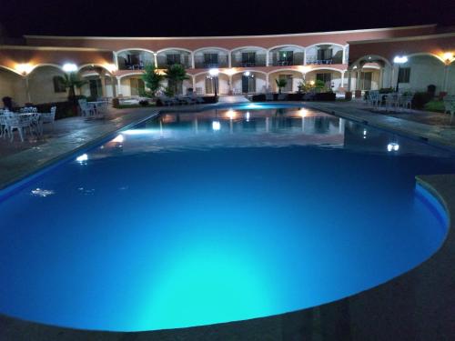 una gran piscina por la noche con luces azules en Hotel Jiménez Plaza en Jiménez