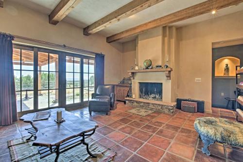 a living room with a fireplace and a table at Charming Mountain Estate with Views and Fire Pit! in Cerrillos