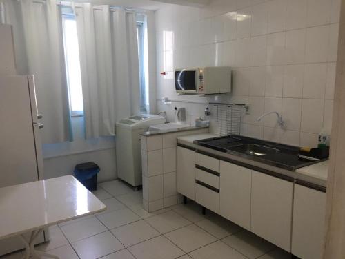 a small kitchen with a sink and a microwave at Apto 3a Avenida Balneário Camboriu in Balneário Camboriú