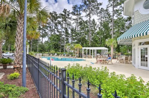 a fence next to a swimming pool with trees at Relax by Pool and Golf Chic Myrtle Beach Condo in Myrtle Beach