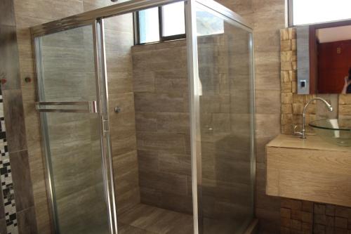 a shower with a glass door in a bathroom at Hostal Dugan in Baños