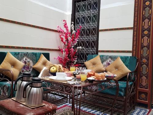 uma sala de estar com uma mesa e um sofá em Dar Atlantic em Fez