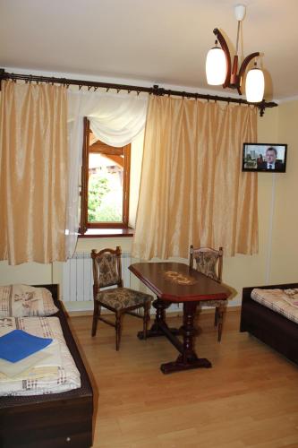 a living room with a table and chairs and a bed at Dom Pielgrzyma in Kalwaria Zebrzydowska