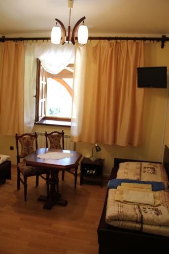 a room with a table and a bed and a window at Dom Pielgrzyma in Kalwaria Zebrzydowska