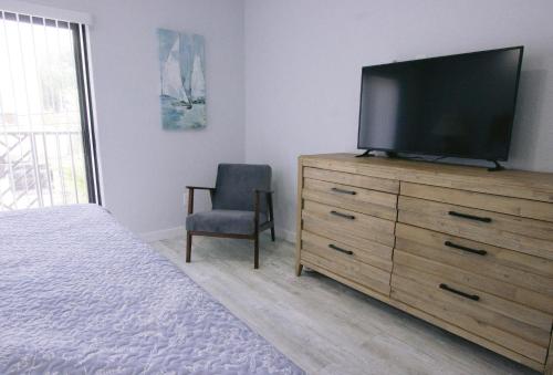 a bedroom with a television on a dresser with a chair at Vistalmar Beach Resort in Deerfield Beach