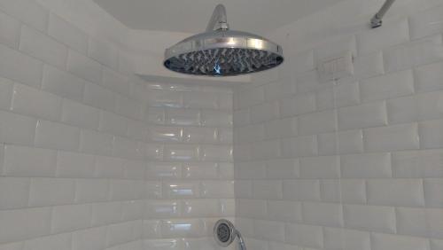 a white tiled bathroom with a shower and a light at Casa 3Bien in Matera