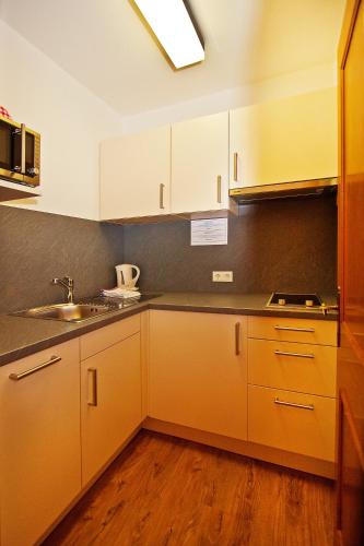 a kitchen with white cabinets and a sink at Ferienwohnungen Appartements Patscheider in Finkenberg