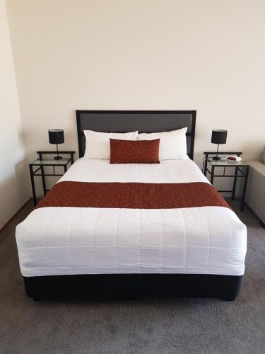 a bedroom with a large bed with two tables at Ararat Colonial Lodge Motel in Ararat