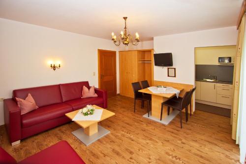a living room with a red couch and a table at Ferienwohnungen Appartements Patscheider in Finkenberg
