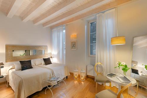 a white bedroom with a bed and a table at Gallery Room in Verona