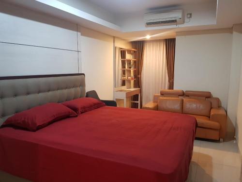 #7 Apartemen The Pinnacle - Louis Kienne Pandanaran Semarang في سيمارانغ: غرفة نوم بسرير احمر كبير واريكة