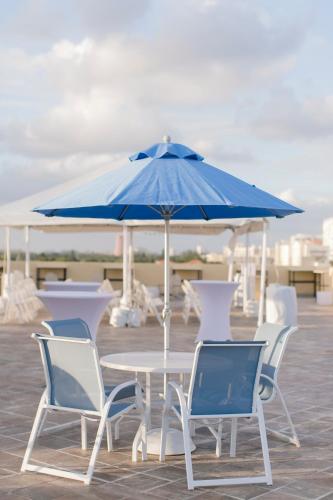 a table and chairs with a blue umbrella at Vistalmar Beach Resort in Deerfield Beach