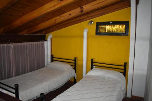 two beds in a room with a yellow wall at Dos ruedas in Mina Clavero