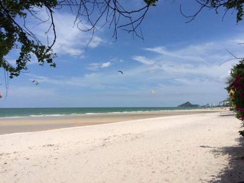 a beach with kites in the sky and the ocean at Cordial serviced apartment in Hua Hin