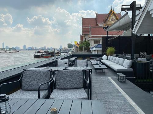 a rooftop patio with couches and tables and the water at Theatre Residence in Bangkok