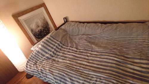 ein Bett mit einer blau-weißen gestreiften Decke in der Unterkunft UNLOCK SAKAI in Sakai