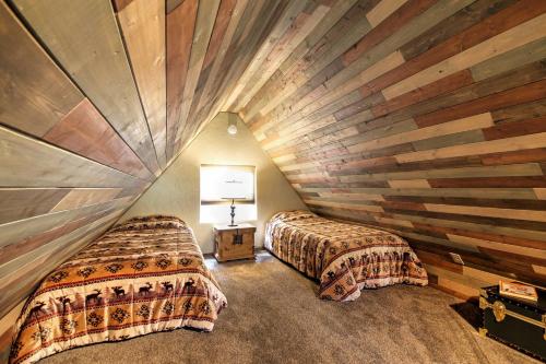 two beds in a room with a wooden wall at Hillside Cripple Creek Cabin with Hot Tub, Mtn Views! in Cripple Creek