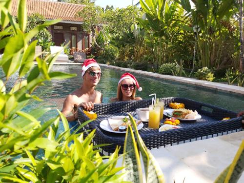 a man and woman wearing santa hats in a swimming pool at Ayuna Family Ubud in Ubud