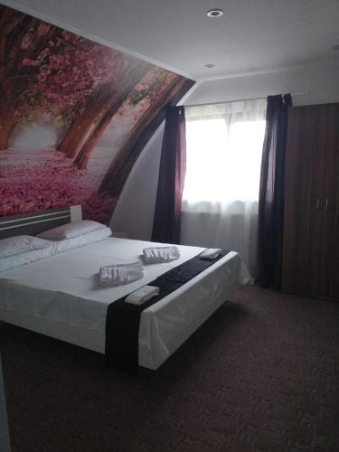 a bedroom with a bed with a painting on the wall at Hotel Hobby in Hunedoara