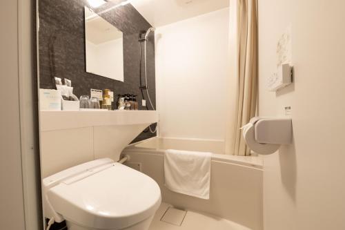 The Celecton Tsuchiura Ekimae في تسوشيورا: حمام ابيض مع مرحاض وحوض استحمام