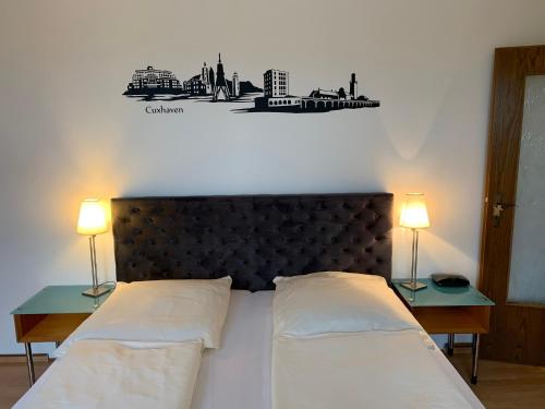 a bedroom with a large bed with two lamps on tables at Pension Appartementhaus Hus Möhlenbarg in Cuxhaven