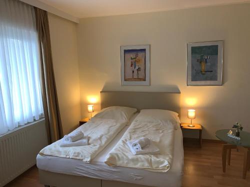 a bedroom with a white bed with two towels on it at Pension Appartementhaus Hus Möhlenbarg in Cuxhaven