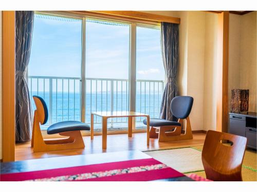 a room with chairs and a table and a large window at Tenku Yubo Seikaiso in Beppu