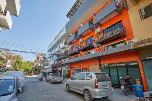 a street with cars parked in front of a building at GO INN Chiang Mai University - CMU in Chiang Mai