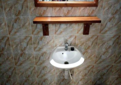 a bathroom with a white sink on a tiled wall at Piccola Beach in Sassako Bégniny