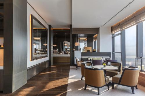 a restaurant with tables and chairs and windows at Rosewood Phnom Penh in Phnom Penh