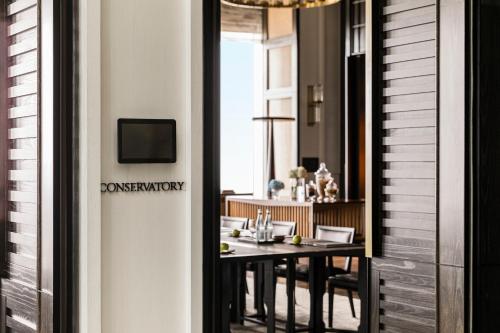 a dining room with a table and a television at Rosewood Phnom Penh in Phnom Penh