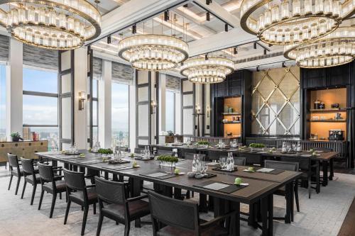 a dining room with a long table and chairs and chandeliers at Rosewood Phnom Penh in Phnom Penh