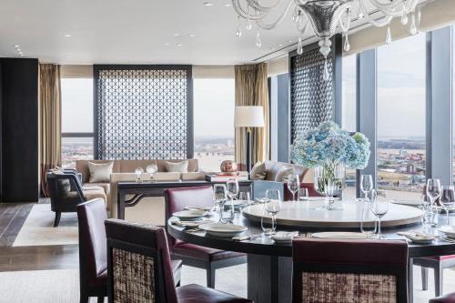 a dining room with tables and chairs and a large window at Rosewood Phnom Penh in Phnom Penh