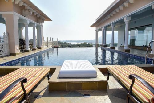 a pool with two benches in front of a building at Jhadol Vijay Vilas Near Lake Pichola in Udaipur