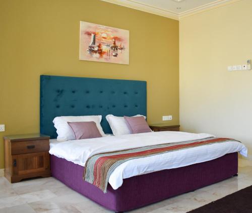 1 dormitorio con 1 cama grande y cabecero azul en Muscat Villa en Mascate