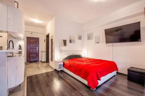 1 dormitorio con cama roja y TV de pantalla plana en Studio Residence Militari M6, en Roşu