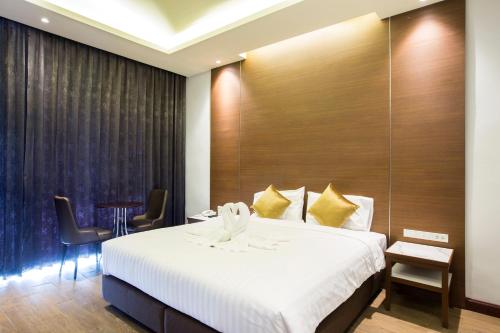 a hotel room with a bed and a table and chairs at Southern Airport Hotel Hatyai in Hat Yai