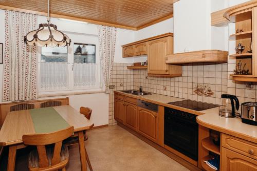 une cuisine avec des armoires en bois et une table avec des chaises dans l'établissement Ferienwohnung Hartlieb Goldeck Millstättersee, à Spittal an der Drau