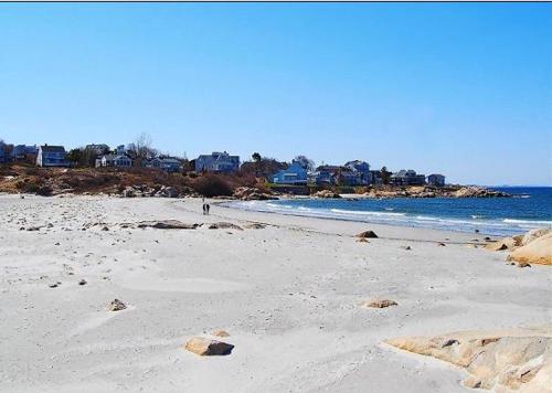 a sandy beach with houses in the background and the ocean at Elegant Gloucester Beach Getaway with Ocean Views! in Gloucester