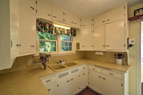a kitchen with white cabinets and a sink and a window at Family-Friendly Fish Creek Cape House with Deck! in Fish Creek
