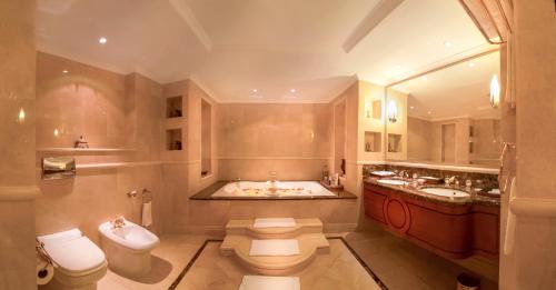 a bathroom with a tub, toilet and sink at Corniche Hotel Abu Dhabi in Abu Dhabi
