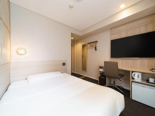 a hotel room with a bed and a desk and a tv at Super Hotel Midosujisen Esaka in Suita