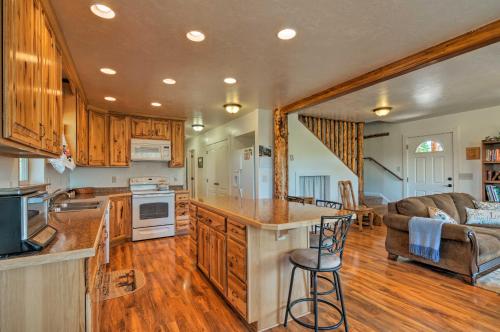 a kitchen with wooden cabinets and a living room at Cozy Henrieville Cabin 18 Mi to Bryce Canyon NP! in Henrieville