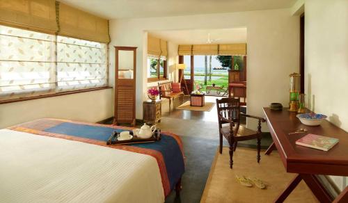 a bedroom with a bed and a desk and a table at amã Stays & Trails, Pathiramanal Villa in Alleppey