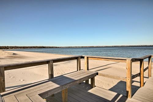 a wooden bench sitting on a beach next to the water at Walk to Beach Long Island Wine Country Home! in Cutchogue